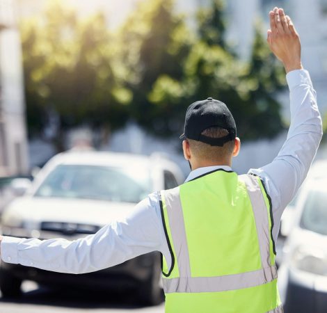 Rearview shot of a traffic warden guiding vehicles outdoors